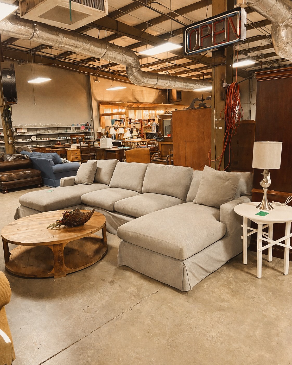 Inside the East Cooper Home Store: a sectional sofa, wooden coffee table, lamps, and home goods on the sales floor