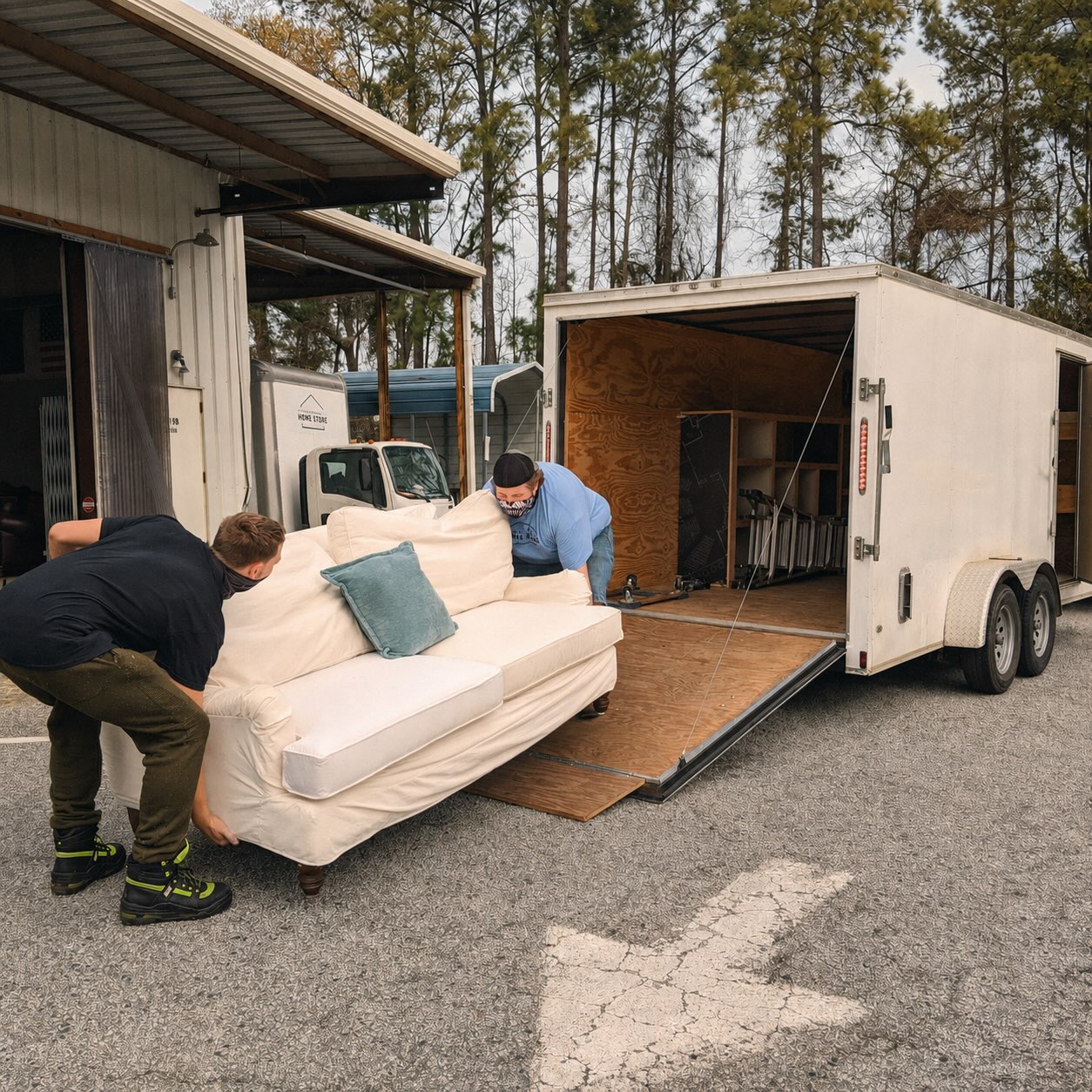 Two volunteers loading a sofa into an enclosed Home Store donation trailer